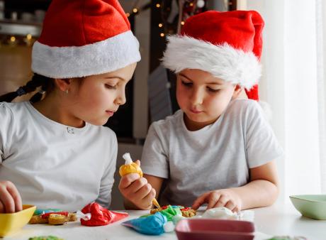 kids in santa hats decorating cookies