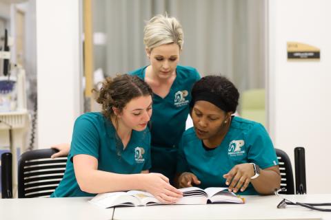 three female adn student looking at a book