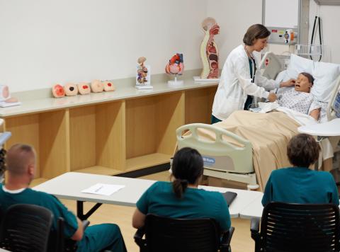 Teacher in scrubs chekcing on patient