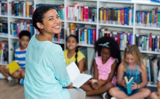 female teacher with book and young children students