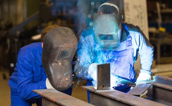welding teacher showing student a weld